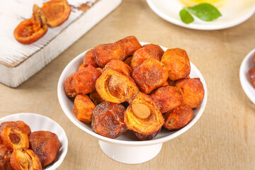 Dried Xinjiang Apricots with Pits in White Bowl on Wooden Table - Healthy Natural Snack Food