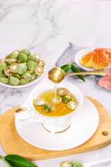 Fresh Kumquat Herbal Tea with Honey and Sliced Citrus Fruit in White Teacup on Marble Surface