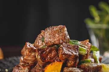 Glazed Beef Cubes with Herbs and Vegetables on Dark Background - Premium Cut Meat Dish