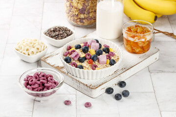 Nutritious Oatmeal Breakfast Bowl with Berries Yogurt Blocks and Honey on White Wooden Background