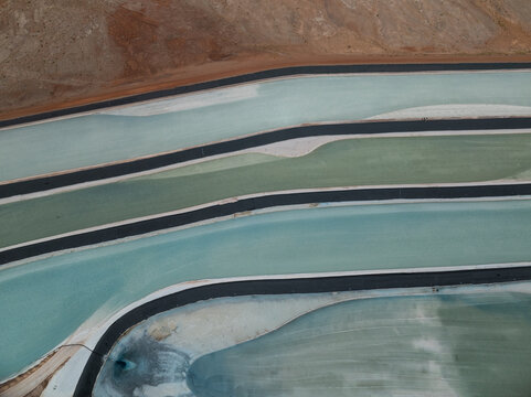 Aerial view of the vibrant potash ponds, their otherworldly hues contrasting sharply with the dark barriers, creating a surreal geometric landscape, Moab, Utah, United States.
