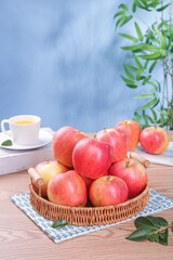 Fresh Red Fuji Apples from Xinjiang in Wicker Basket on Wooden Table with Tea Cup