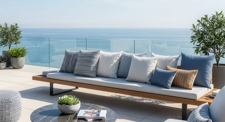 A modern outdoor patio with a long wooden sofa varied cushions a marble table plants and an ocean view under a clear sky