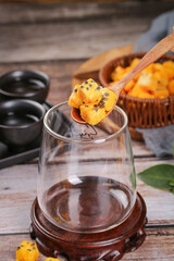 Freeze dried passion fruit block on wooden spoon over tea glass with bamboo basket of instant fruit pieces