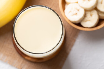 Top view of banana milk in glass with sliced banana and fruit