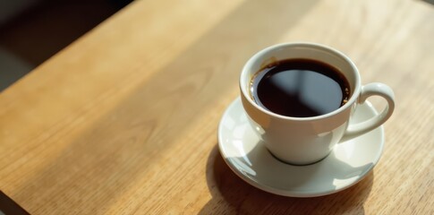 Full ceramic coffee cup, half-full, sits on clean, light oak desk, surface, light