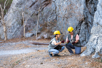 Two Female geologists working in the field Rock and mineral exploration in natural environments. Scientific teamwork in geological research study data by observation rock inspection on mountain.