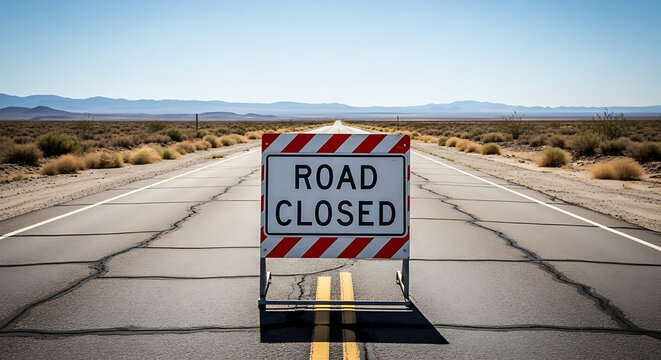Road Closed Barrier on a Hot Asphalt Road with a Desert Landscape Background
