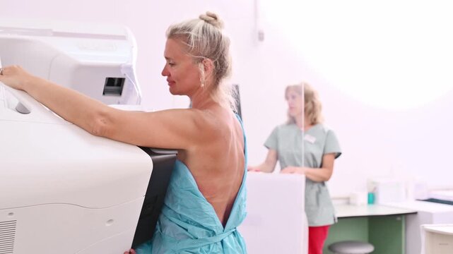 50-year-old woman undergoes mammography procedure on special medical equipment mammograph with the help of assistant in modern clinic. Regular medical examination, screening for breast cancer	
