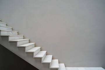 Minimalist modern interior staircase with clean white marble steps and a smooth gray wall background