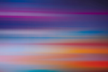 Abstract horizontal streaks of vibrant purple blue pink orange and yellow light creating a dynamic and energetic background