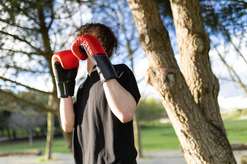 Young man wearing boxing gloves practicing in park