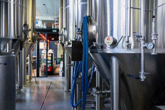 stainless steel beer brewing tanks inside modern brewery, industrial fermentation equipment for craft beer production in brewery facility
