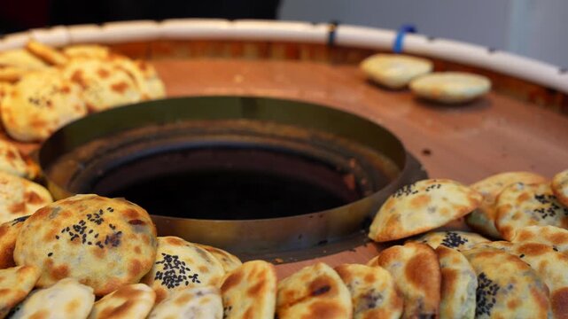 Hand picks fresh, traditional sesame shaobing order from hot tandoor oven