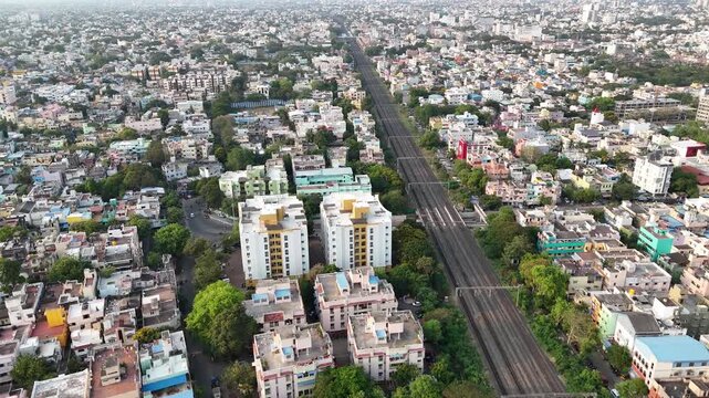 Aerial footage of Railway tracks dominate the frame, running through a densely populated area. A tranquil temple tank with trees offers a natural focal point within the sprawling metropolis.