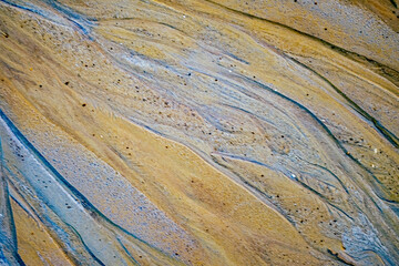 Obraz premium textured multicolored sand surface at abandoned kaolin mine, the patterns resemble streaks of natural sediment layers, creating a dynamic, abstract visual effect.