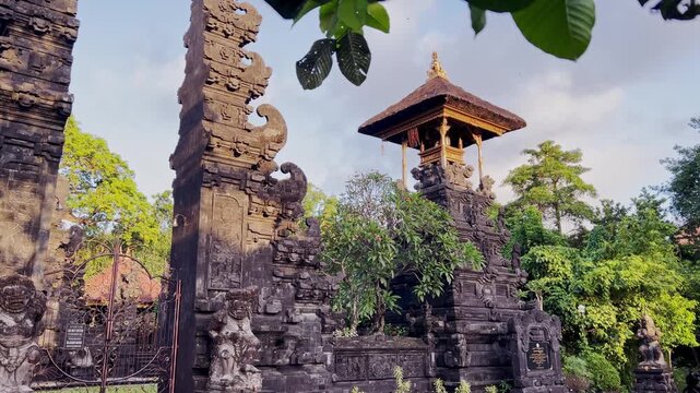 This Bali Hindu temple features an ornate split gate and gate tower crafted from lava rock stone, surrounded by vibrant gardens, creating a serene holy site steeped in Balinese tradition.