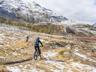 Bernina, Switzerland - October 5th 2024: Two bikers on a trail along the Bernina train line.