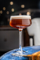 Elegant cocktail in evening glass. A crafted cocktail sits on a blue table, glowing in the evening lights.