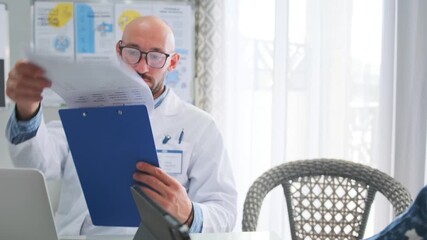 Group of doctors and researchers in white coats discuss reports and data during hospital seminar. Senior specialist reviews documents, colleagues use laptops and tablets to analyze medical innovation. - Powered by Adobe