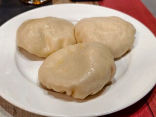Three steamed dumplings on a white plate ready to eat a delicious meal at a restaurant table