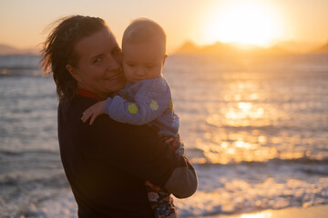 Mother holding her child on sunet. Sea view.