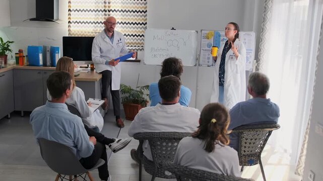 Woman with coffee cup passionately presents pharmaceutical product at hospital seminar, gesturing and debating with bald chief doctor holding documents. Medical staff listen about new medicine.