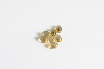 golden softgel capsules on white background, vitamins or omega 3 supplements