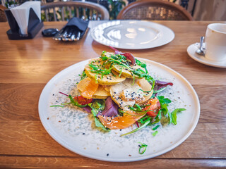 Healthy Breakfast Stack: Delicious Layers of Smoked Salmon, corn fritters, Mixed Greens, and Cherry Tomatoes, Drizzled with Dressing.Perfect for a Nutritious Start.Artisanal Brunch Plate