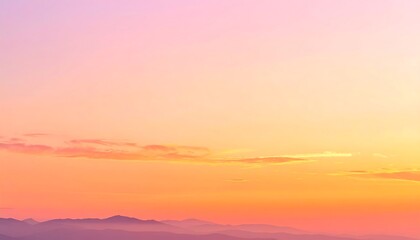 Obraz premium A serene, colorful sunset paints the sky in soft hues of orange, pink, and yellow, with hazy mountain ranges in the distance.