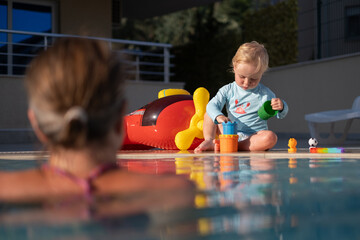 Mother and baby in outdoor swimming pool of tropical resort. 