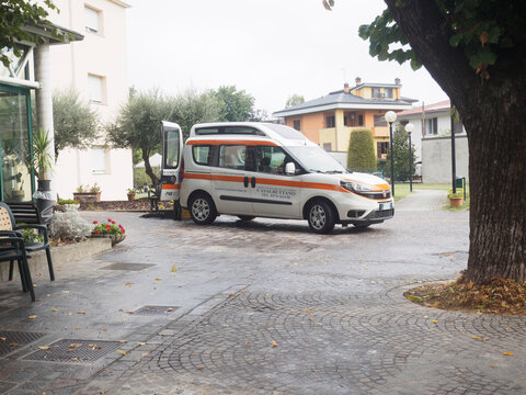 White Fiat Doblo parked near retirement facility, side door open, prepared for senior transportation services