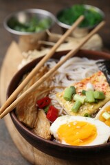 Tasty ramen with enoki mushrooms in bowl on table, closeup