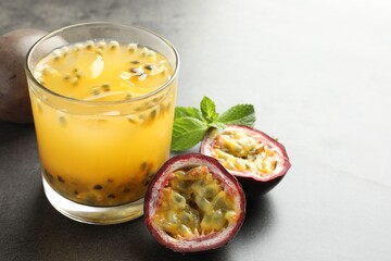 Tasty passion fruit drink with mint and fresh fruits on grey table, closeup. Space for text
