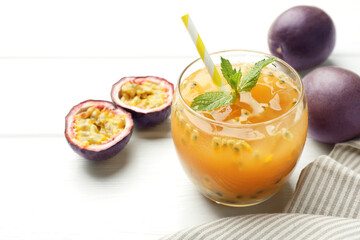 Tasty passion fruit drink with mint and fresh fruits on white wooden table, closeup