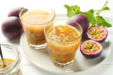 Tasty passion fruit drink and fresh fruits on white wooden table, closeup