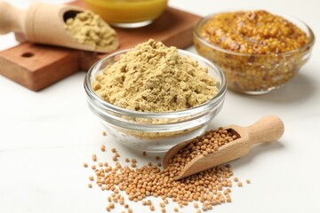 Different types of mustard on white marble table, closeup