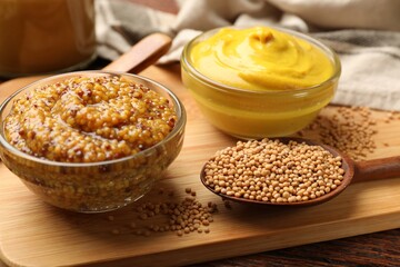 Different types of mustard on wooden table, closeup