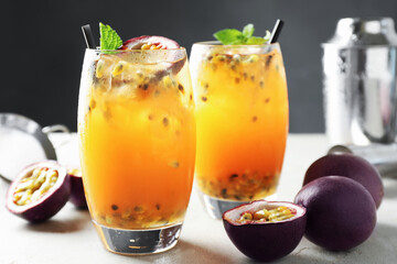 Tasty passion fruit drink with mint in glasses and fresh fruits on gray table, closeup