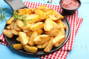 Tasty baked potatoes with rosemary and ketchup on light blue wooden table, closeup