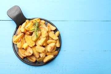 Tasty baked potatoes with rosemary on light blue wooden table, top view. Space for text