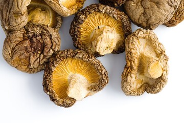 A close-up of dried shiitake mushrooms on white, highlighting their intricate, rustic textures and natural hues.