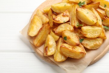 Tasty baked potatoes with parsley on white wooden table, closeup. Space for text