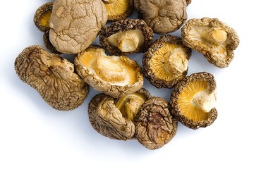 Close-up shot of dried shiitake mushrooms on white, highlighting their intricate surfaces and deep umami hues.