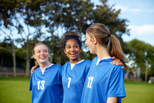 Girls teammates laughing and walking on football field