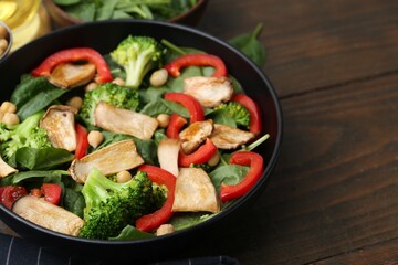 Tasty salad with eryngium mushrooms, chickpeas, vegetables and spinach on wooden table, closeup. Space for text