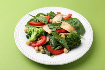 Tasty salad with eryngium mushrooms, chickpeas, vegetables and spinach on green background, closeup