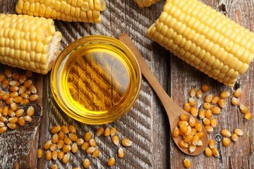 Corn oil, kernels and cobs on wooden table, flat lay