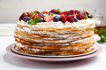 Delicious crepe cake with fresh berries on white wooden table, closeup