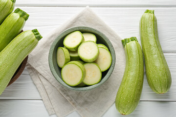 Fresh ripe zucchinis on white wooden table, flat lay. Whole and cut